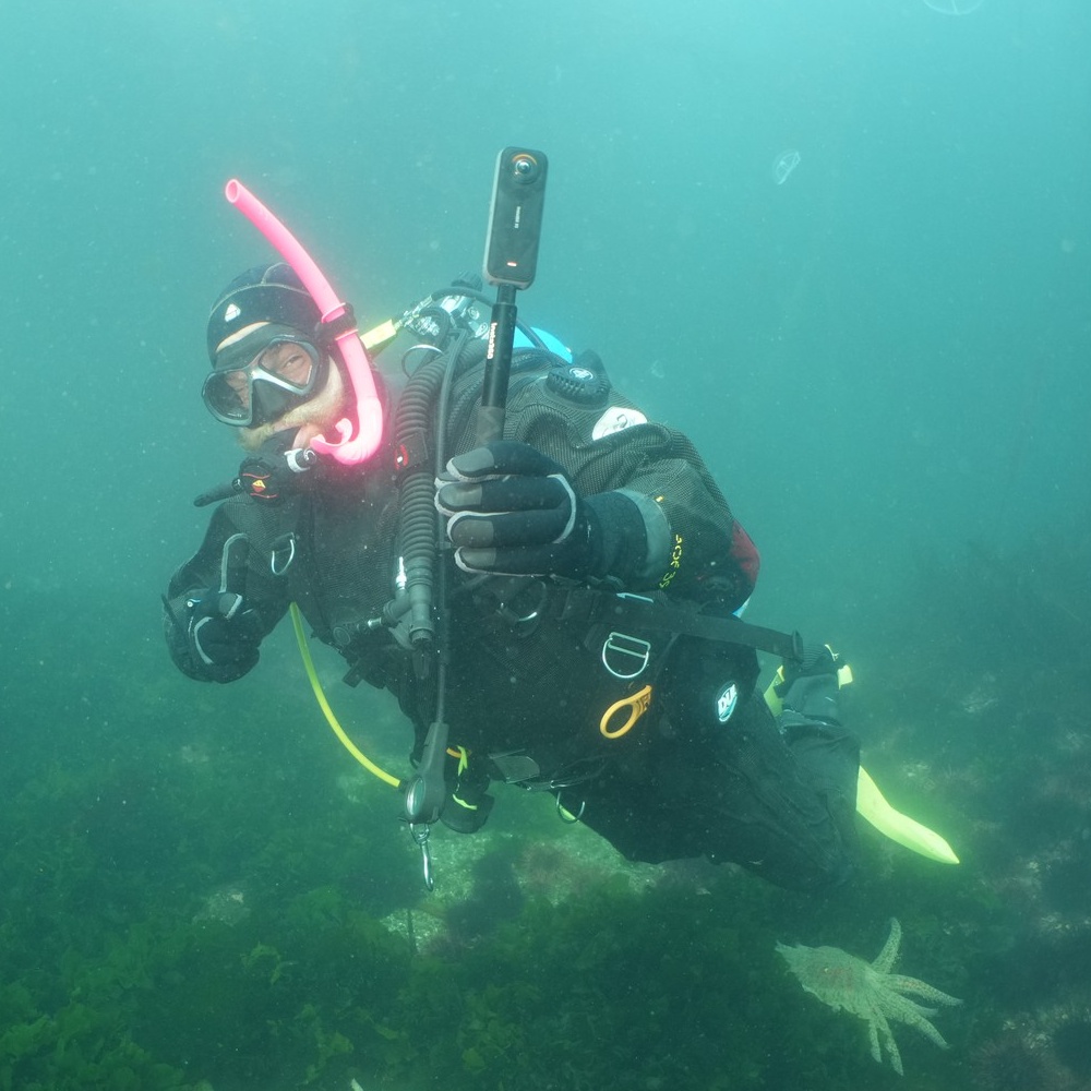 Mitchel McCloskey scuba diving while holding an underwater 360 camera